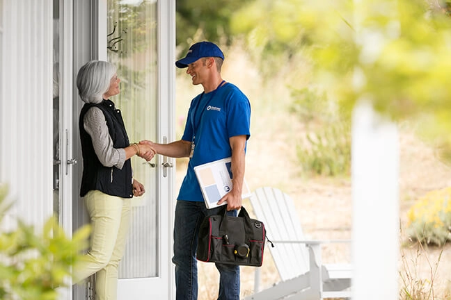Handyman greats homeowner at front door of her home