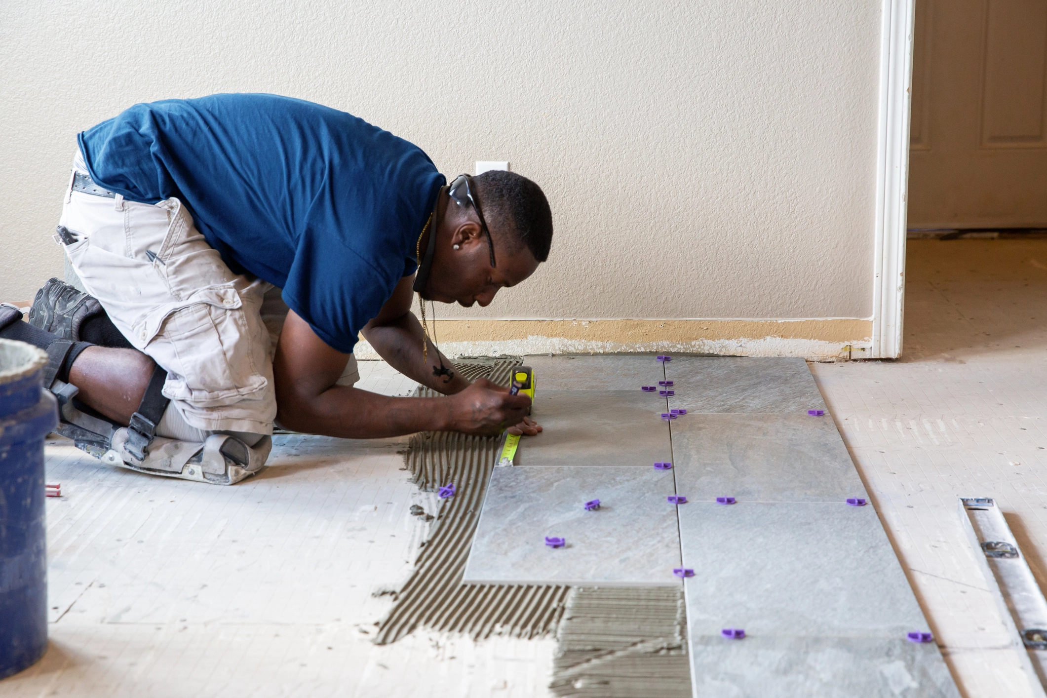 A photo of a Handyman Connection worker installing floor tile in a bathroom