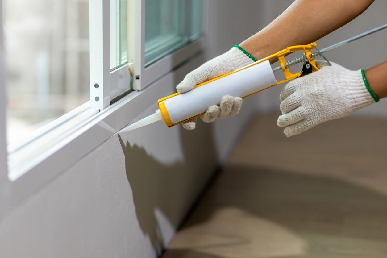 A photo of a caulk gun sealing a window frame