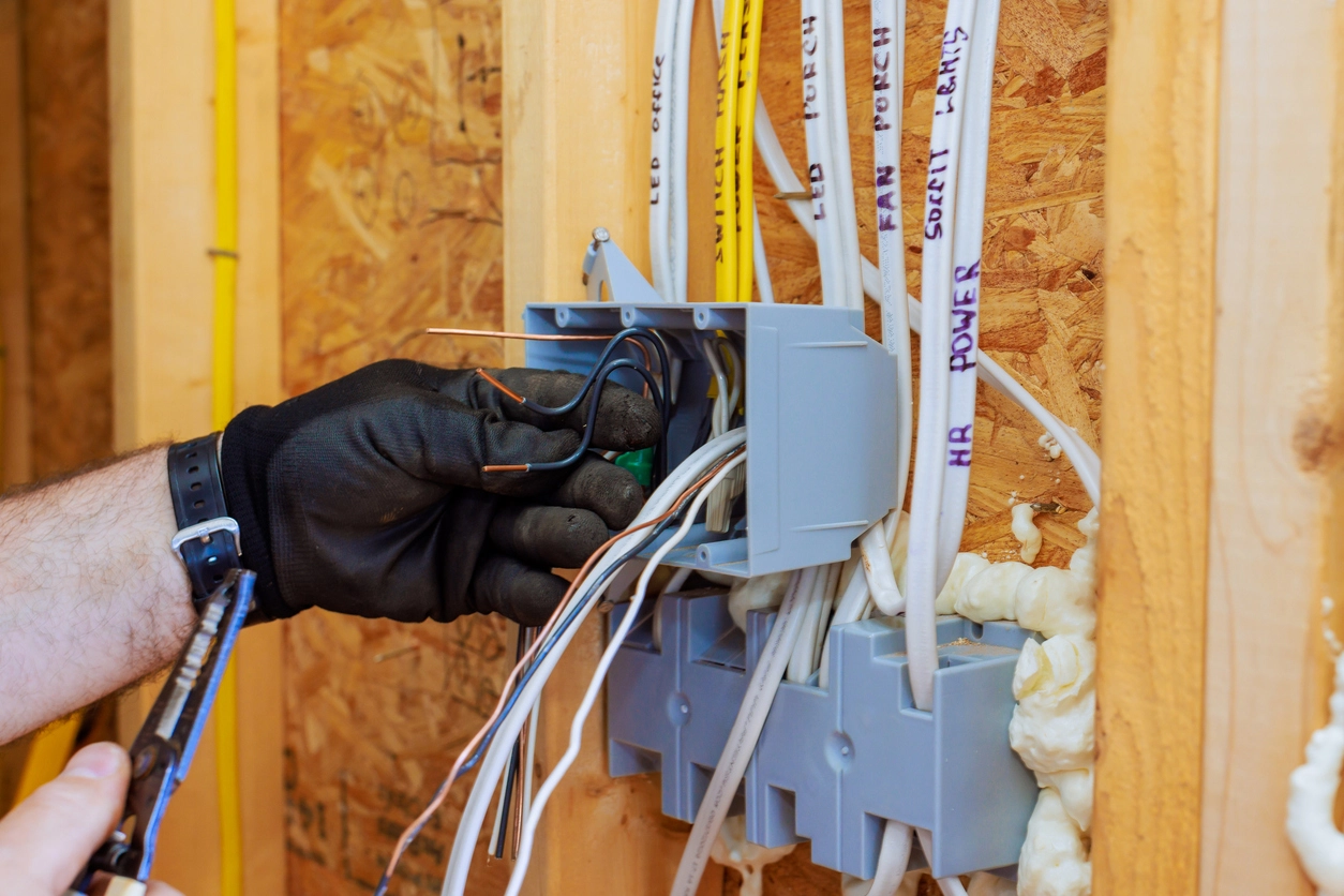 A close up photo of a worker installing electrical wire in a basement