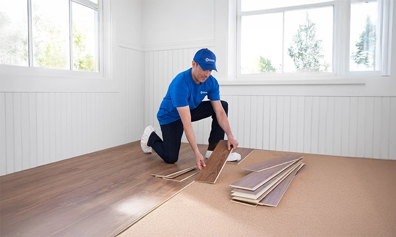 A photo of a Handyman Connection worker laying down flooring panels