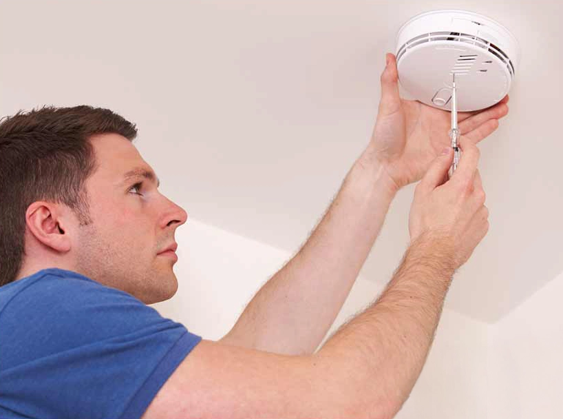 A photo of a Handyman Connection worker installing a fire alarm
