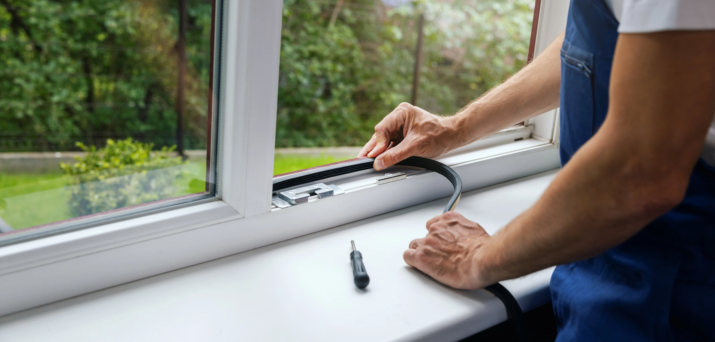 A handyman adding flex tape to a window sill