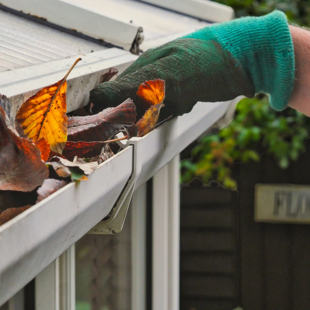 A close up photo of a worker digging leaves out of a customers gutters