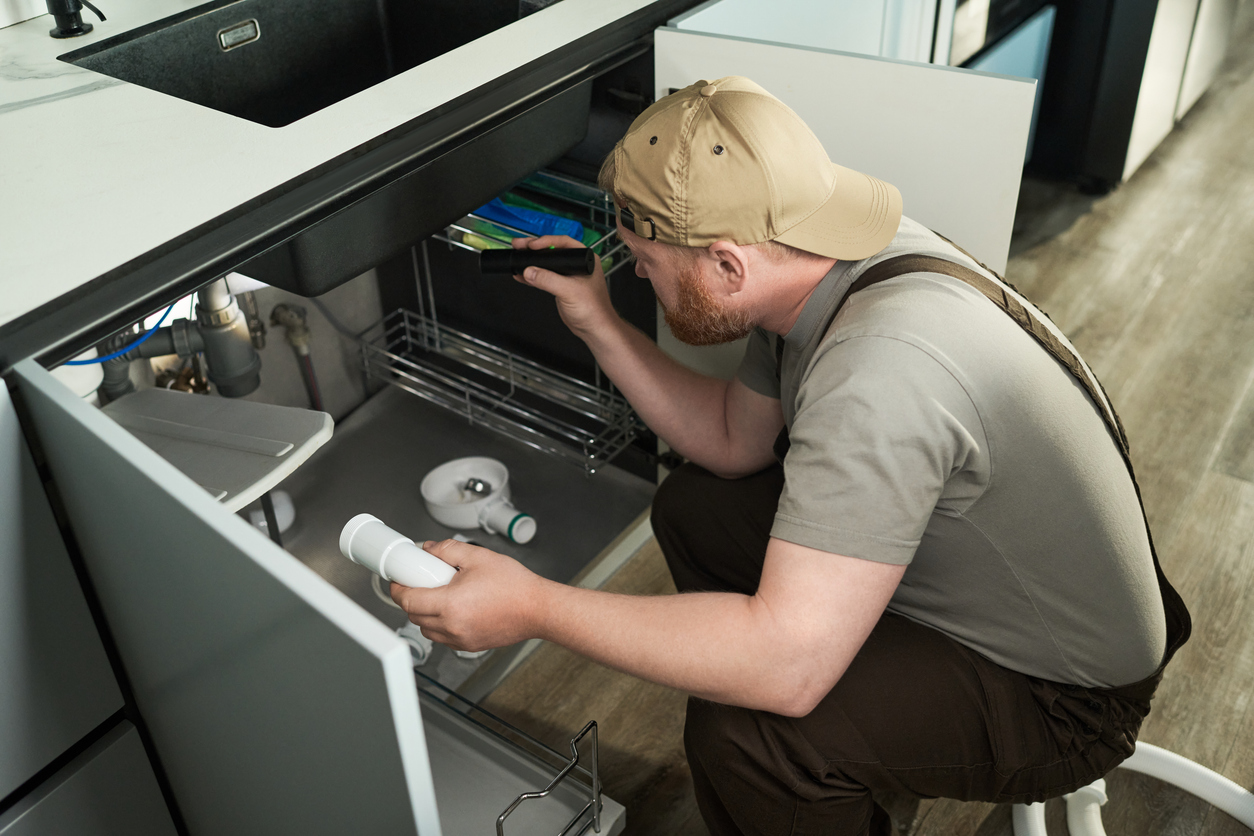 A photo of Handyman Connection checking for leaks under a kitchen sink