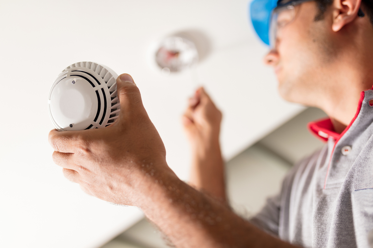 A photo of a HMC worker checking a smoke alarm